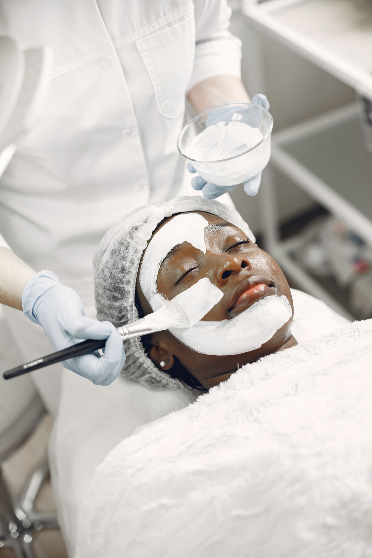 Aesthetician applying a facial mask in a clinical med spa setting