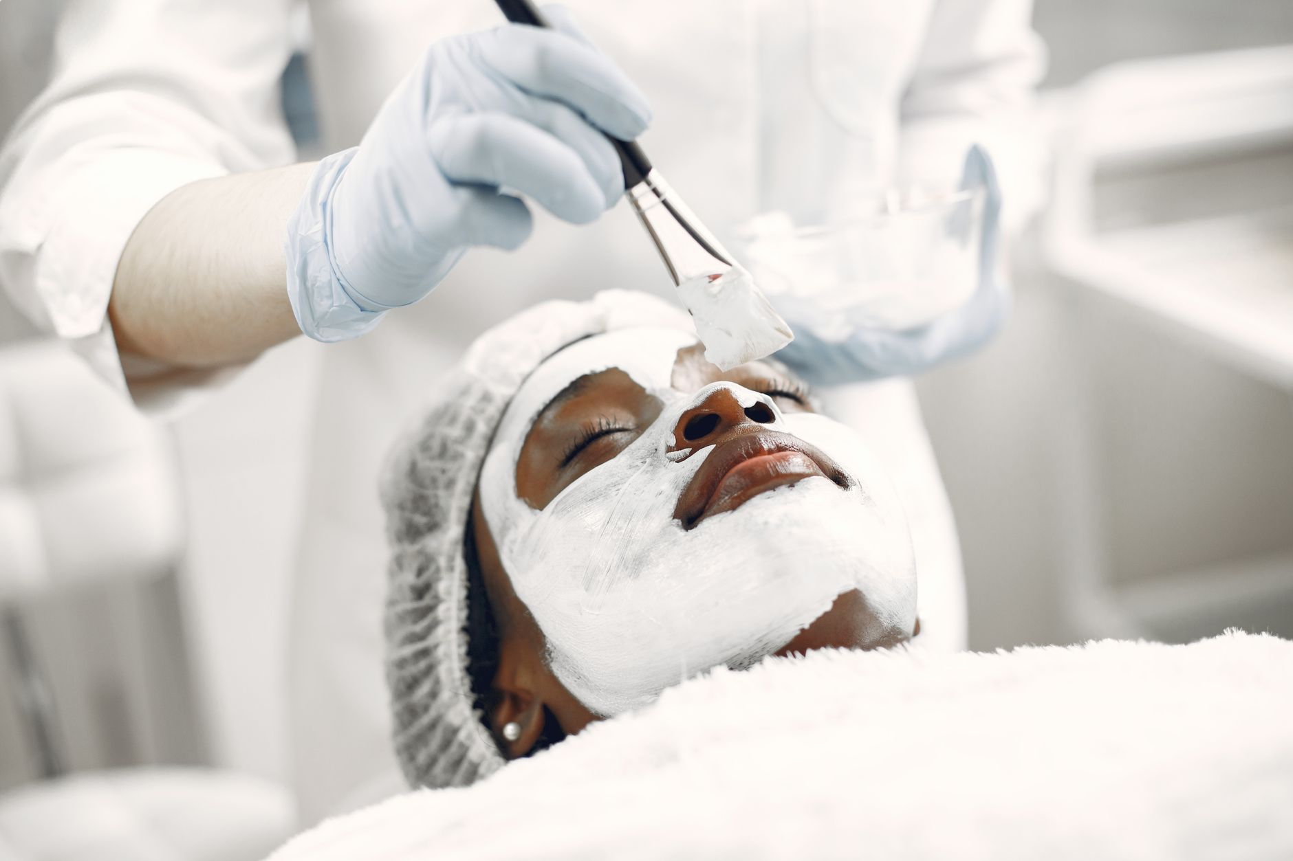 Mains de praticienne effectuant un soin du cuir chevelu à la table Head Spa en cabine professionnelle.