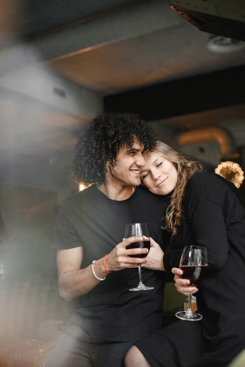 Free A loving couple relaxing indoors with wine, showcasing warmth and intimacy. Stock Photo