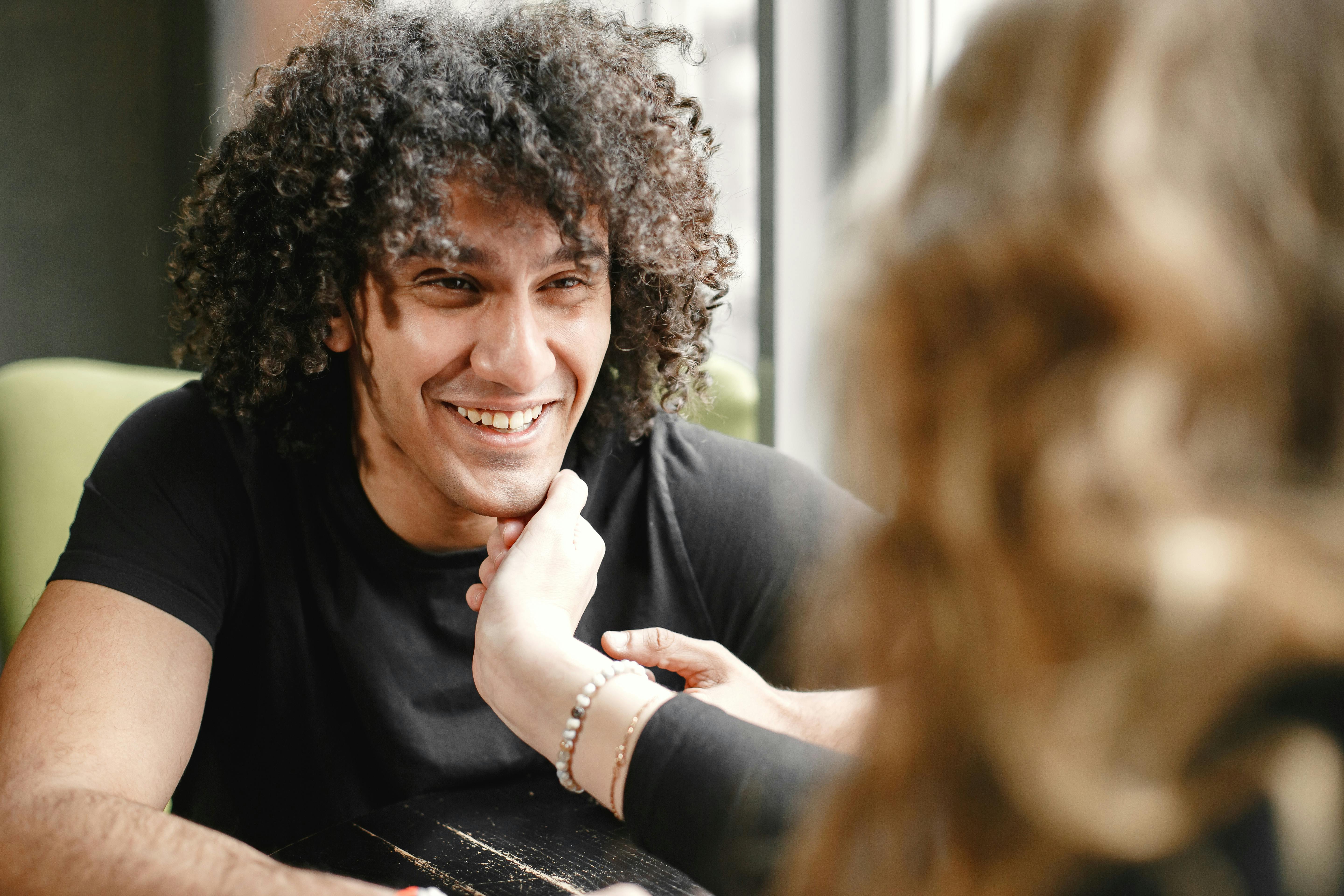 Cuplu într-un moment de intimitate la cafenea, comunicând prin atingere