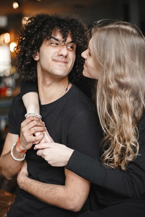 Free Smiling couple hugging indoors with warm lighting, expressing love and joy. Stock Photo