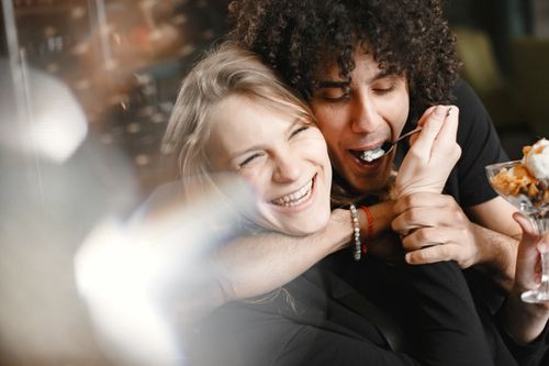 Free A joyful moment of a couple laughing and sharing a dessert, highlighting togetherness and love. Stock Photo