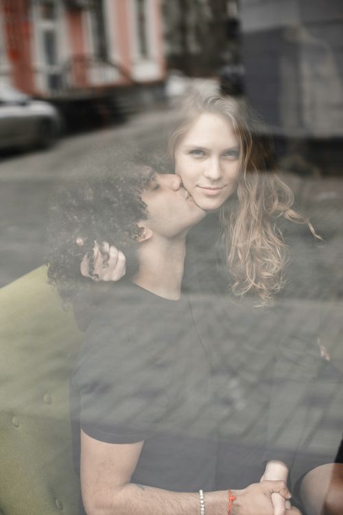 Free A loving couple sharing a tender moment while sitting indoors by a window. Stock Photo