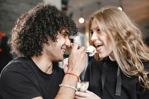Free A loving couple shares a joyful moment feeding each other ice cream indoors. Stock Photo