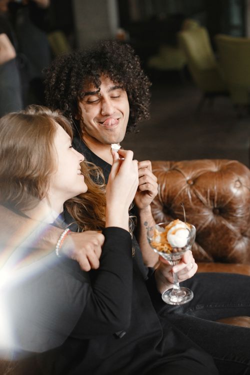Free Happy couple sharing a delightful ice cream moment on a cozy leather couch. Stock Photo