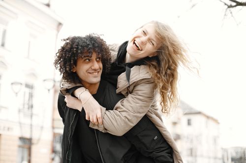 Free Happy couple embracing playfully on a bright day in an urban outdoor setting, showcasing love and joy. Stock Photo
