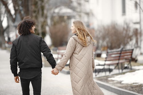 Back View of a Couple Holding Hands and Walking on a Sidewalk in Winter 