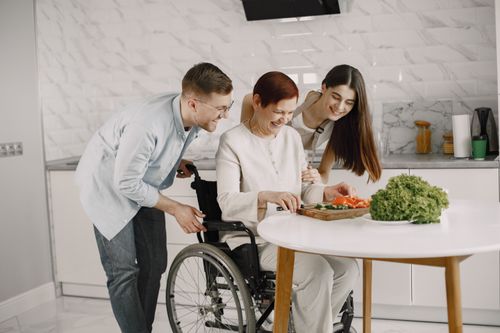 Free A joyful family preparing vegetables in a modern kitchen around a wheelchair-bound member. Stock Photo