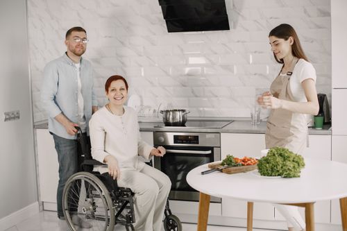 Free Three adults enjoying family time preparing food in a bright kitchen. Stock Photo