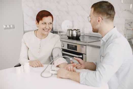 A healthcare professional checks a patient's blood pressure indoors, showcasing a friendly and caring interaction.