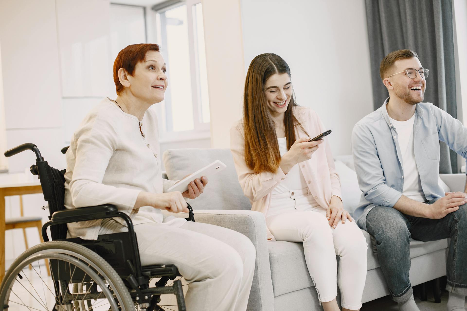 A cheerful group of friends using smartphones and remote control indoors. Inclusive setting.