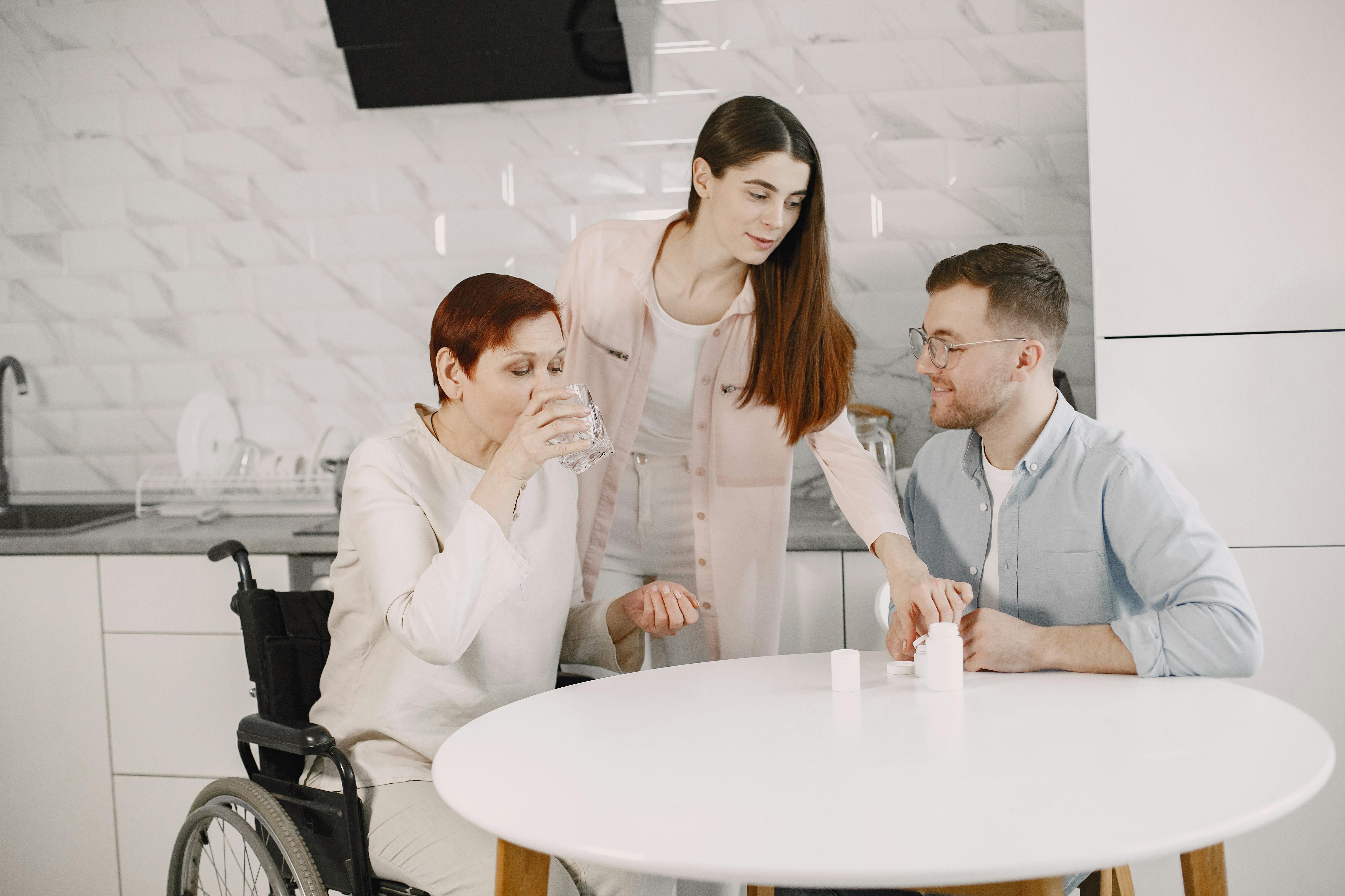 adult care homes near me - Family members providing care and companionship to an elderly woman in a modern kitchen.