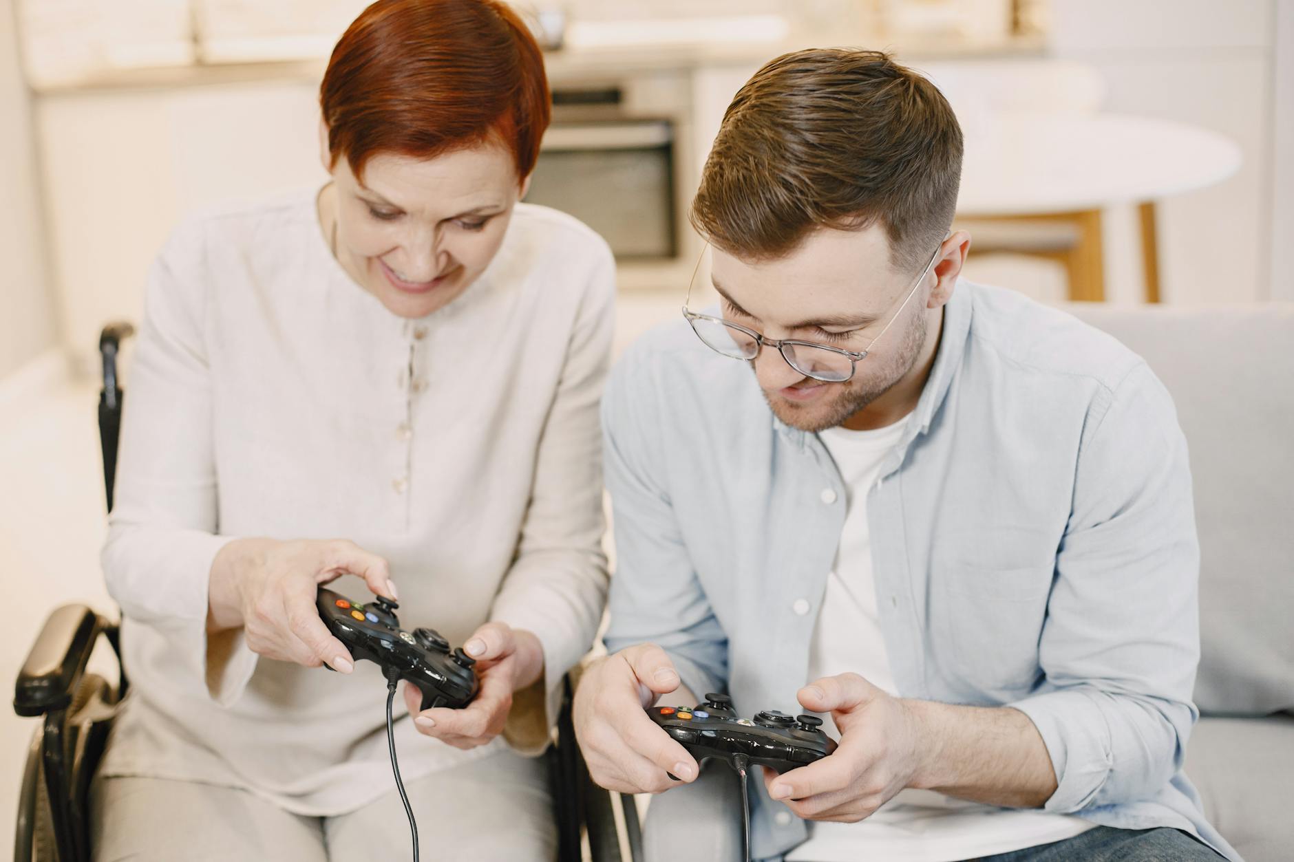 Adult son and senior mom enjoying video games together indoors, fostering connection.
