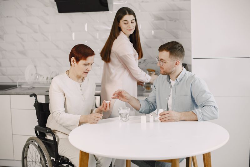 A service provider warmly interacting with young adults with disabilities in a supportive environment.