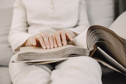 Free A close-up of hands reading a Braille book, emphasizing touch and visual impairment support. Stock Photo