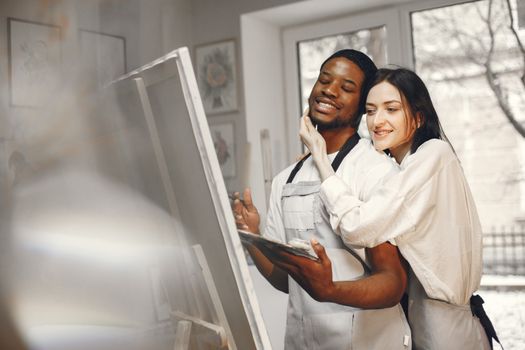 A happy couple painting on an easel indoors, embracing creativity and love.