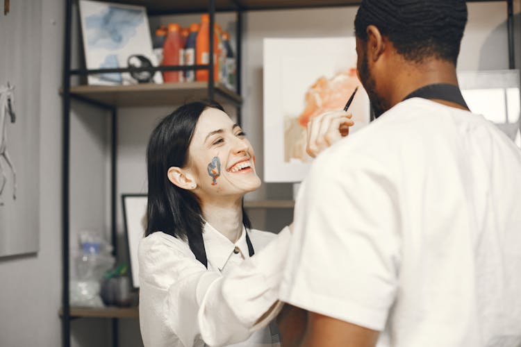 Woman With Face Paint Putting Paint On A Man's Face