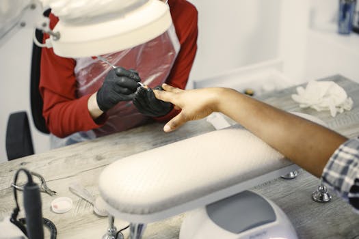Close-up of a manicurist painting nails in a modern beauty salon with gloves on.