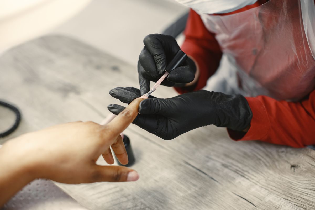 Formatrice en onglerie appliquant une technique avec des gants d'hygiène, organisme de formation beauté