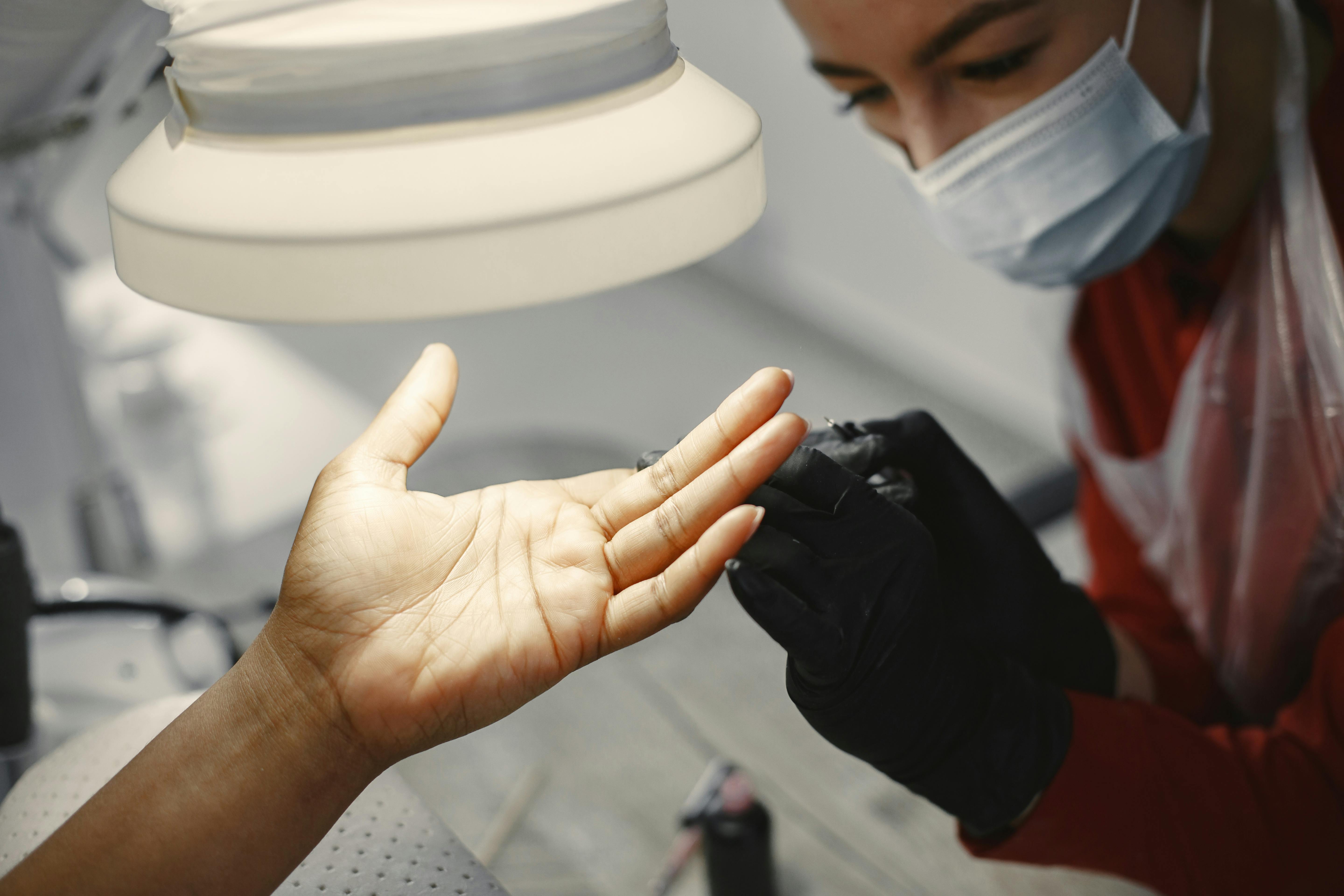 Close-up of a manicure session with focus on hands and tools under bright salon lights.