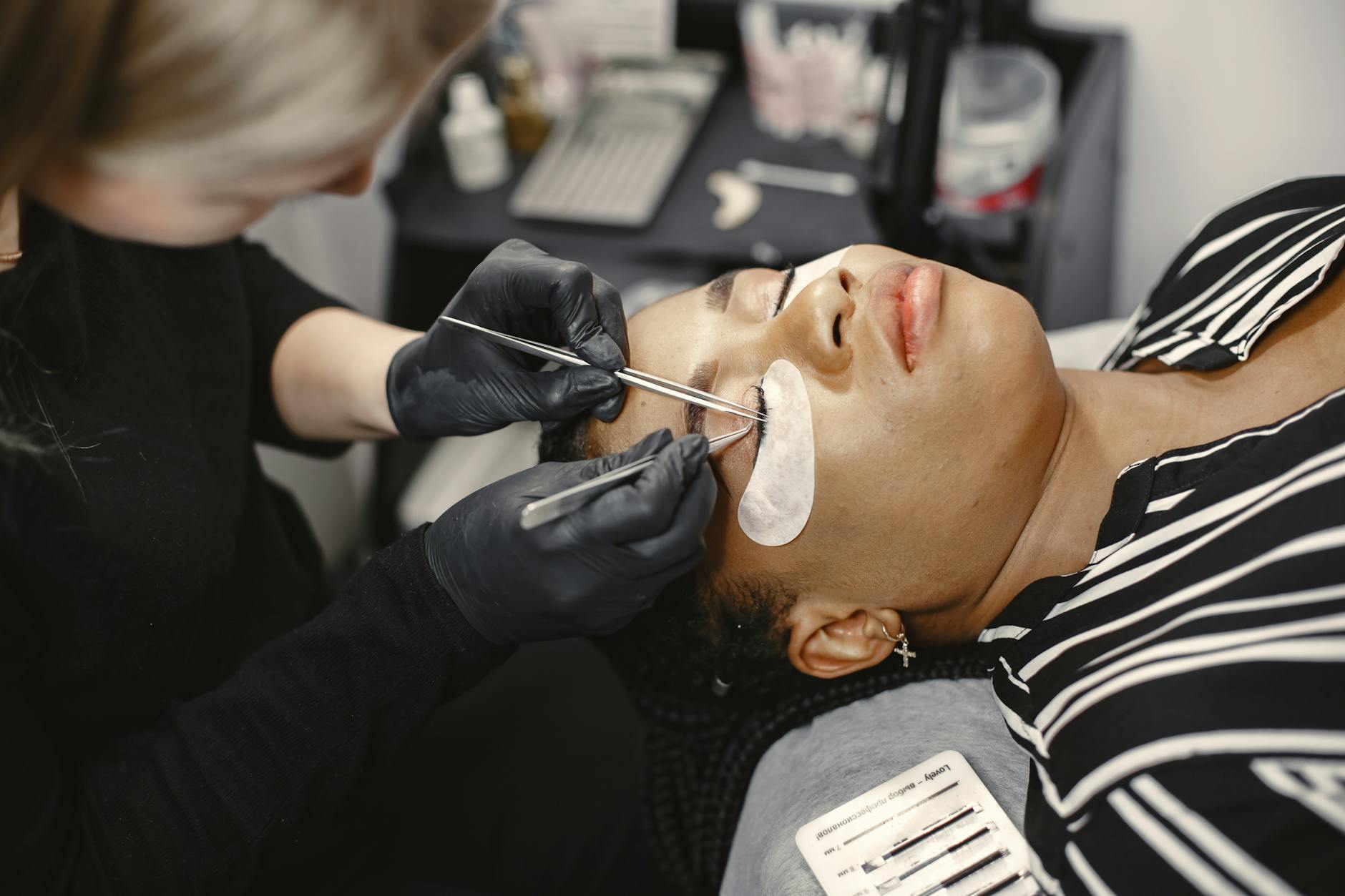 Beauty treatment with a technician applying eyelash extensions to a client in a salon setting