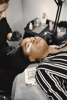 Expert applying eyelash extensions to a client in a salon setting with tools and accessories.
