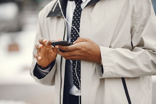 Close-up of a businessman using a smartphone and headphones outdoors.
