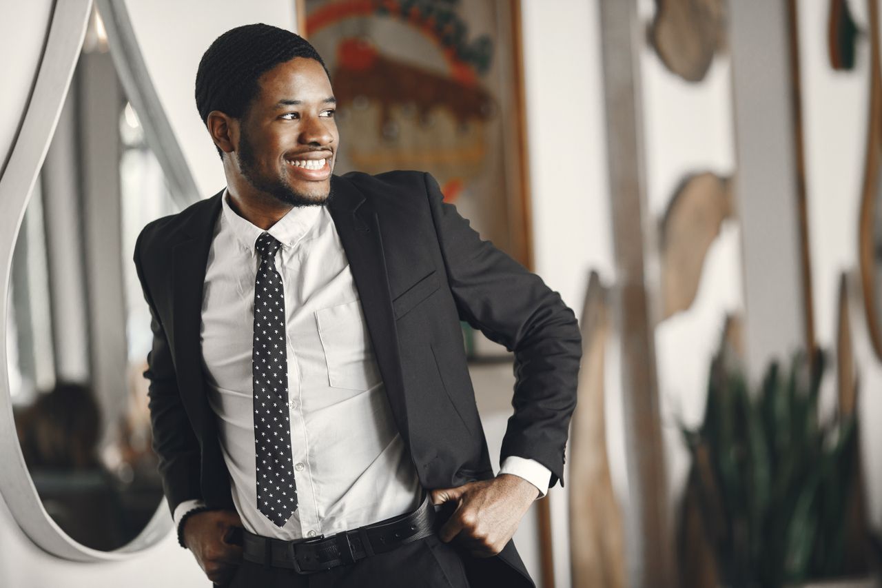 smiling man in a suit adjusting his belt exuding confidence in an indo