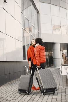 Couple embracing with suitcases outside a modern building, showcasing travel and relationship themes.