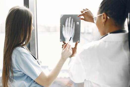 Two doctors examine a hand X-ray in a hospital setting.