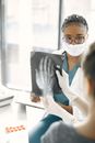 A Woman Wearing a Facemask Looking at the Person Holding Photographic Film