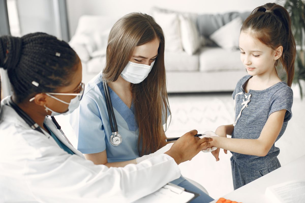 Pediatric healthcare team examining a school-age child during a home visit