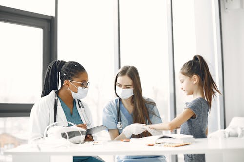 Free Medical Professionals Wearing Facemasks while Checking the Girl Stock Photo