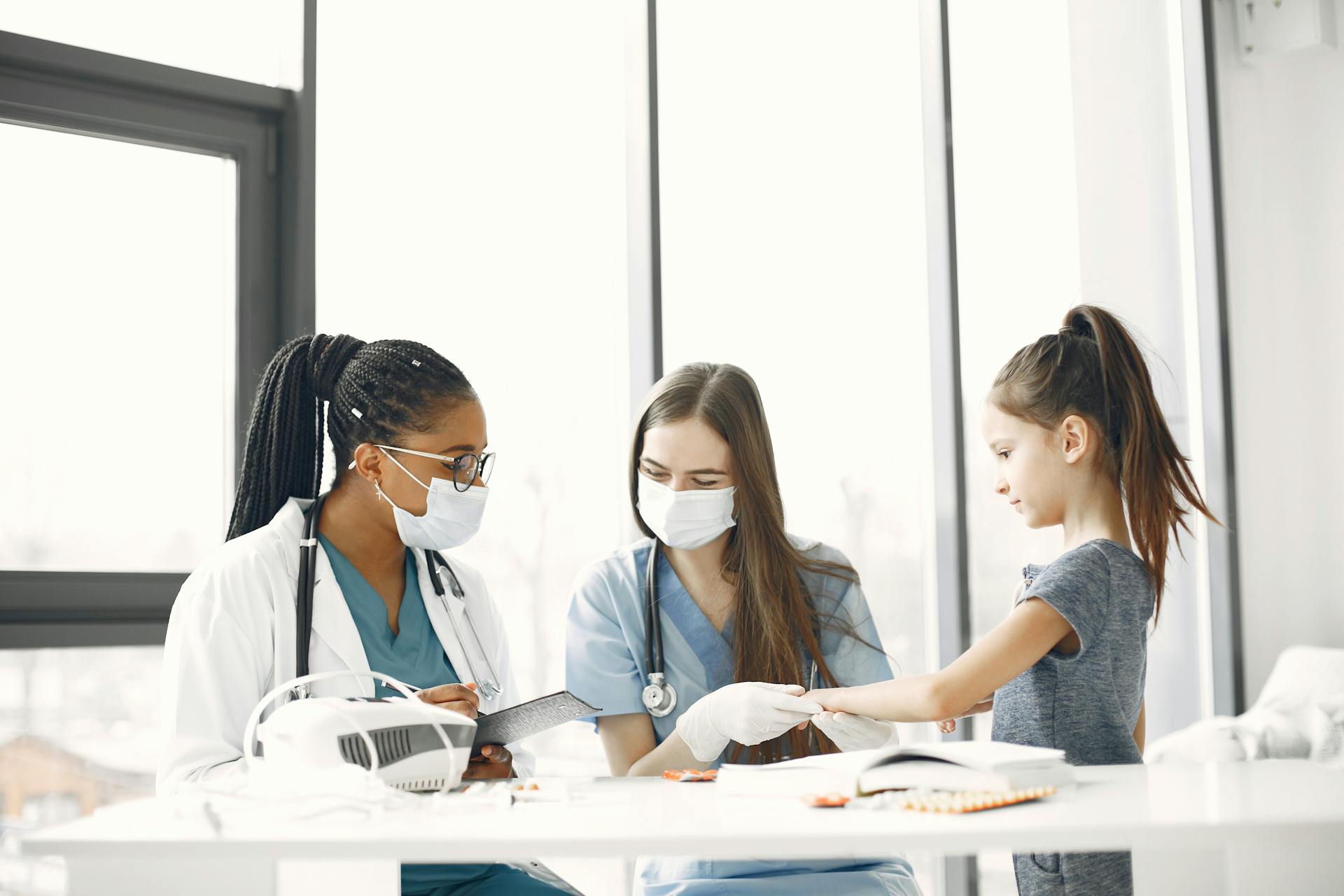 Healthcare professionals attending to a child indoors during a medical check-up.