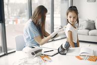 Young girl in clinic receiving a checkup from a female doctor with stethoscope.