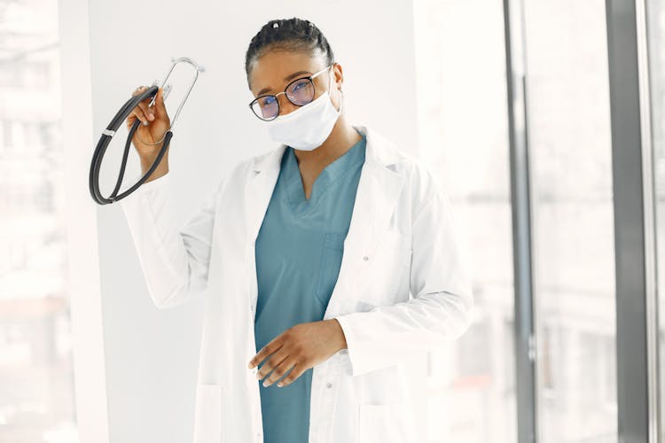 A Health Worker In White Lab Gown Holding A Stethoscope