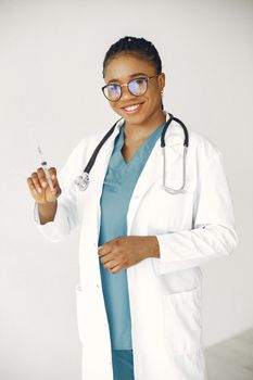 Portrait of a cheerful female doctor in a lab coat holding a syringe.