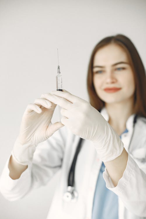 A Medical Professional Looking at the Syringe she is Holding