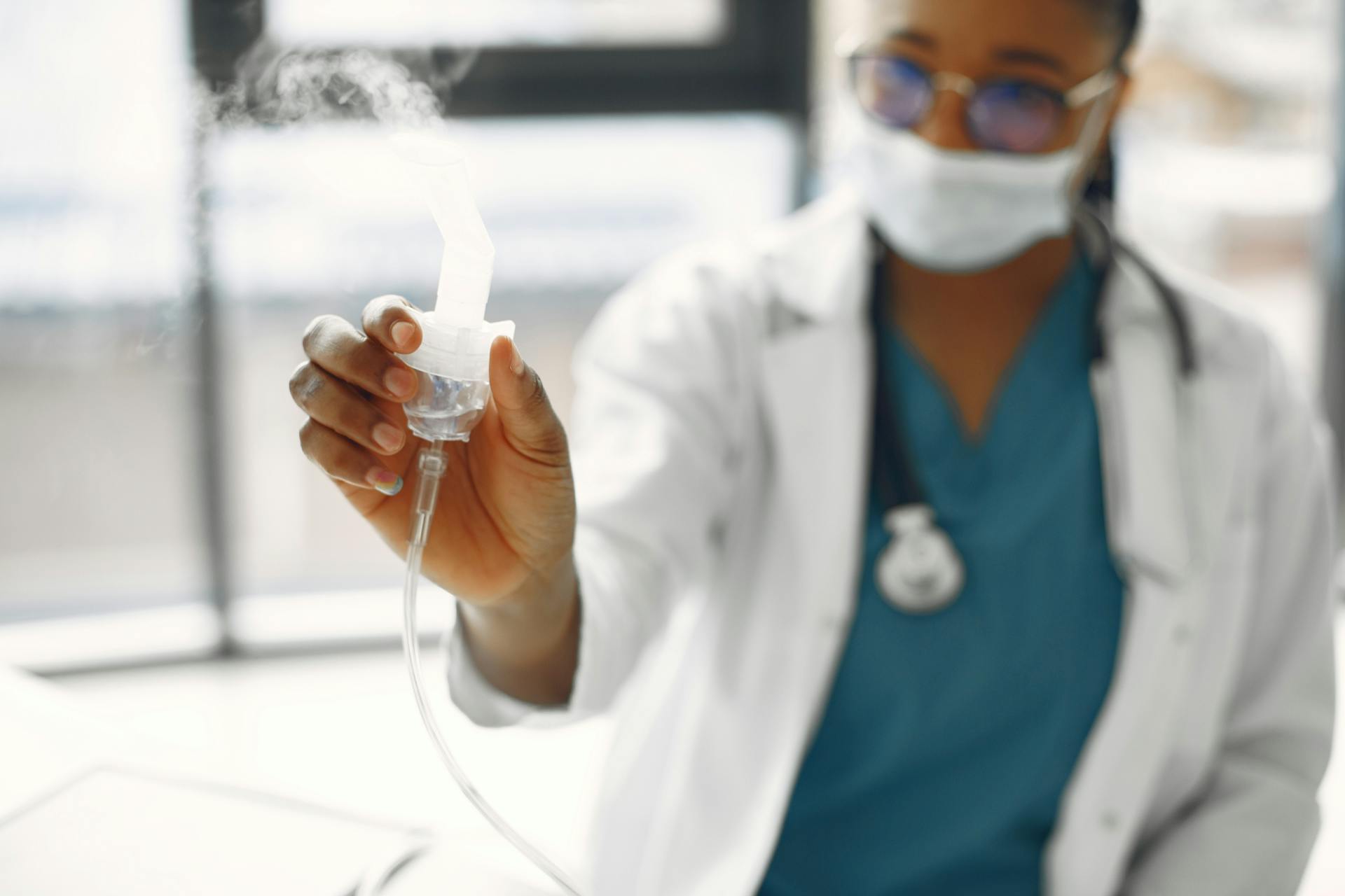 Close-up of a healthcare worker holding a nebulizer, showing focus on medical equipment.