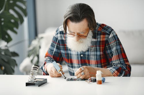 Close-Up Shot of a Bearded Man in Checkered Long Sleeve Using Electronic Equipment