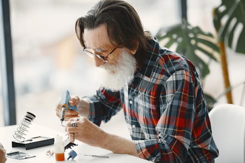 Close-Up Shot of a Bearded Man in Checkered Long Sleeve Using Electronic Equipment