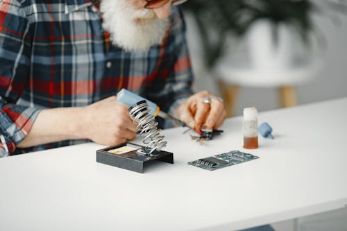 Close-Up Shot of a Bearded Man in Checkered Long Sleeve Using Electronic Equipment