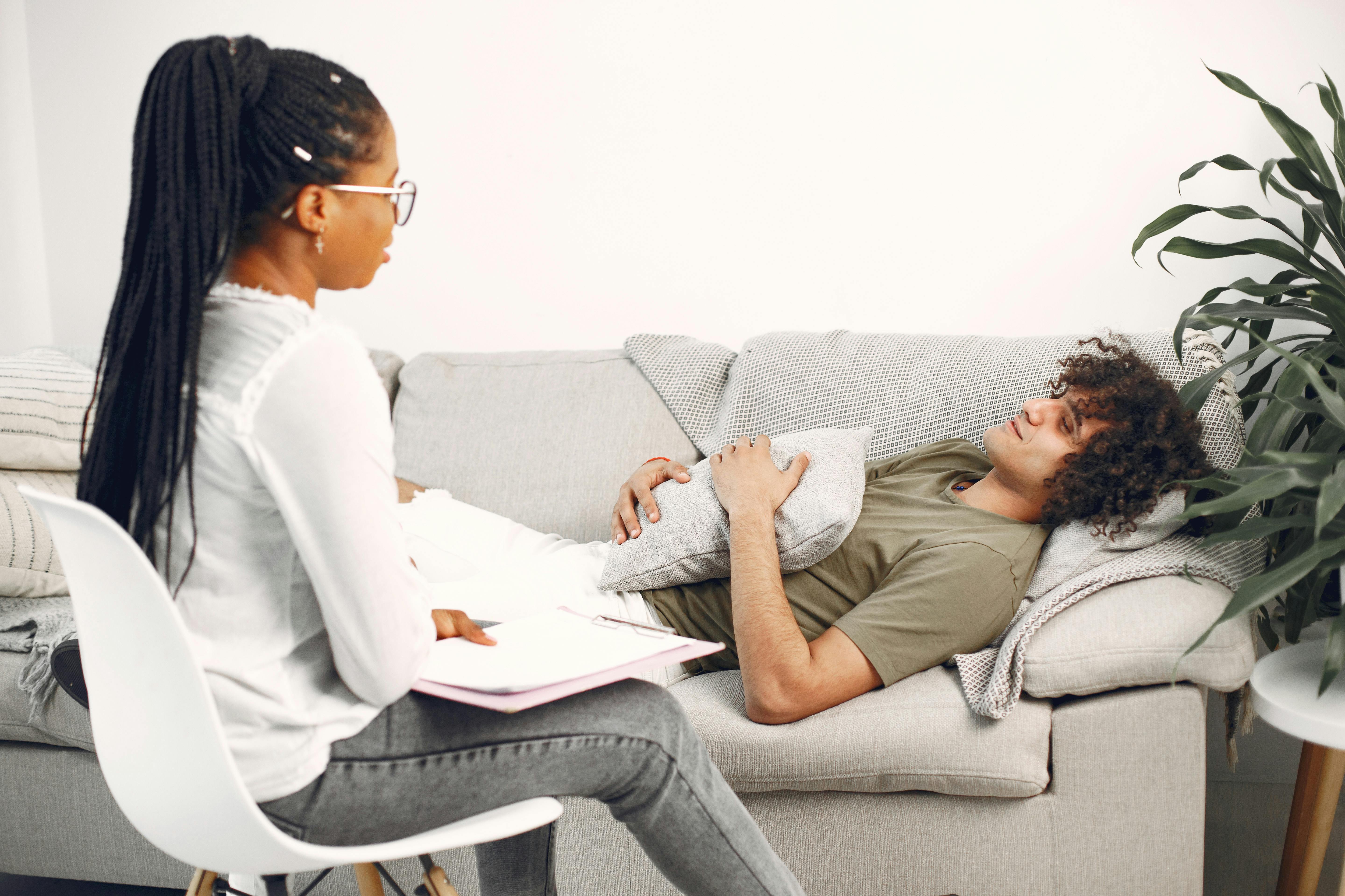 A female therapist taking notes while the client is lying on the couch