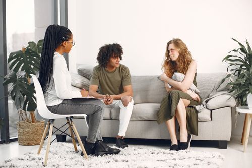 Free A diverse group engaged in a therapy session in a stylish, modern living room. Stock Photo
