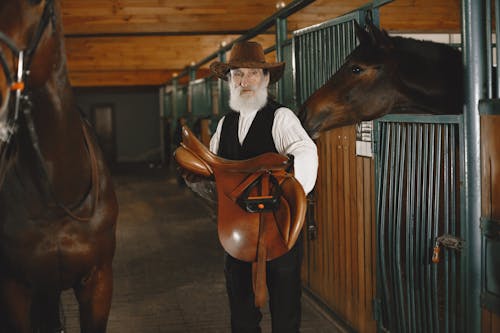 An Elderly Man Carrying A Saddle