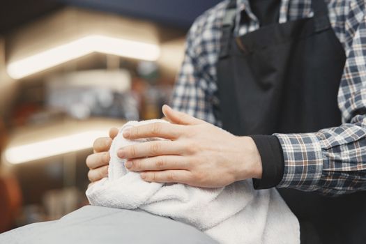 Close-up of a barber using a towel for a facial treatment in a barbershop setting.