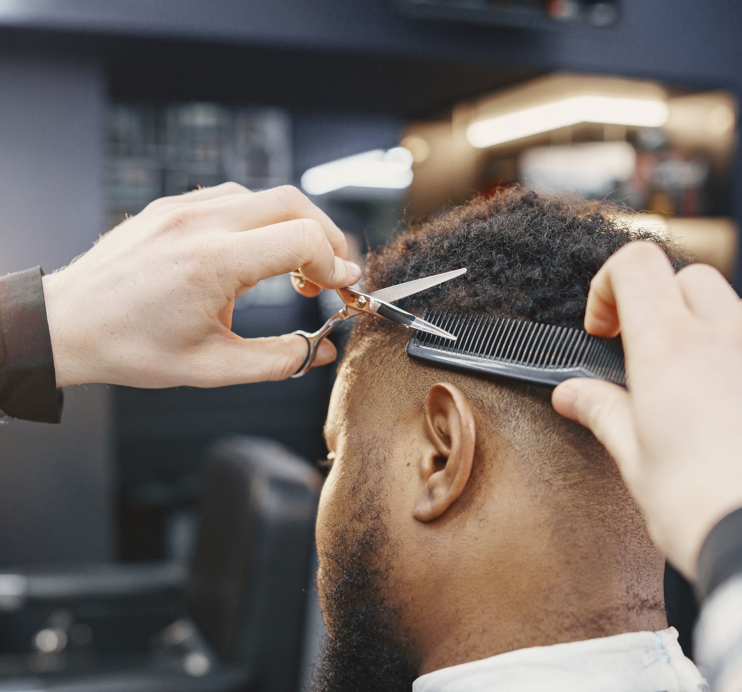 Close-up of a barber giving a haircut with scissors and comb in a modern salon.