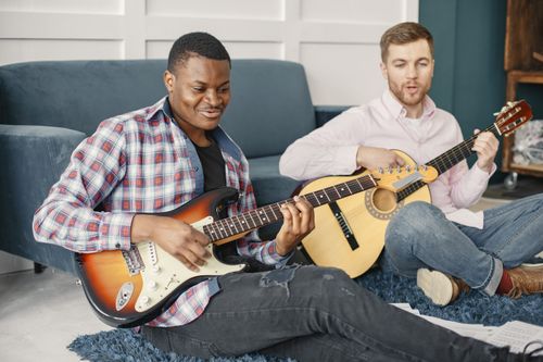 Free Two men enjoying a music session with guitars in a cozy, indoor setting. Stock Photo