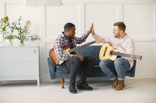 Men Playing Guitars and High Fiving on a Couch 