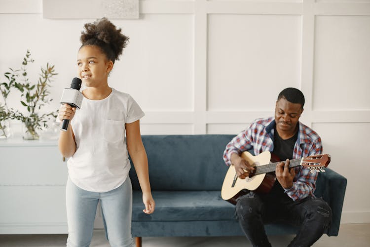 Father Playing The Guitar And Daughter Singing 